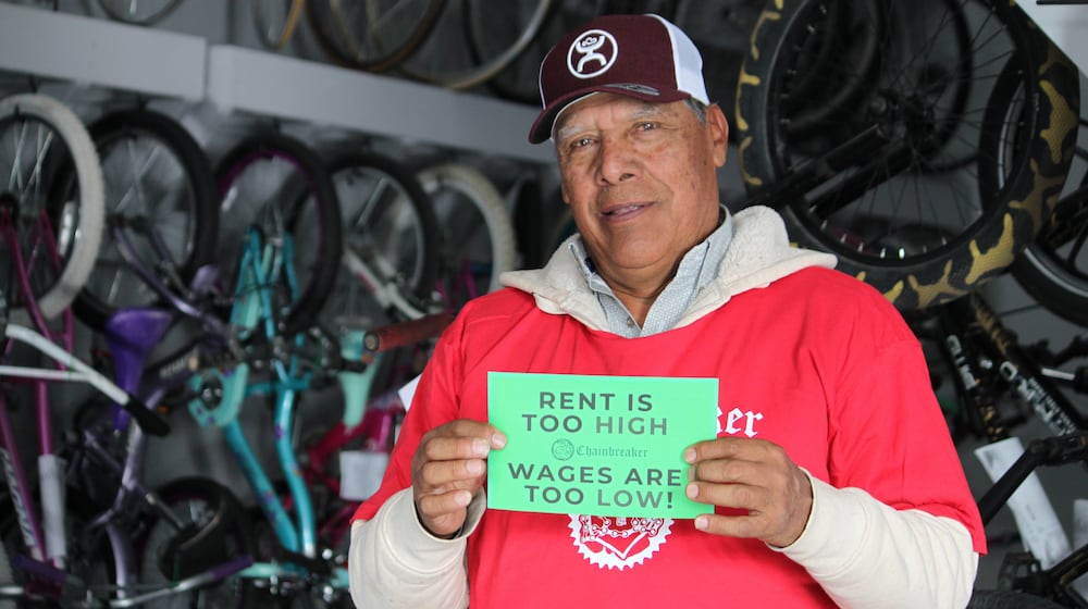 Ismael Cortes Estrada poses for a photo holding one of the signs advocates used in the campaign for updating the city's minimum wage law, in Santa Fe, New Mexico, on Wednesday, Nov. 26, 2025. (AP Photo/Susan Montoya Bryan)