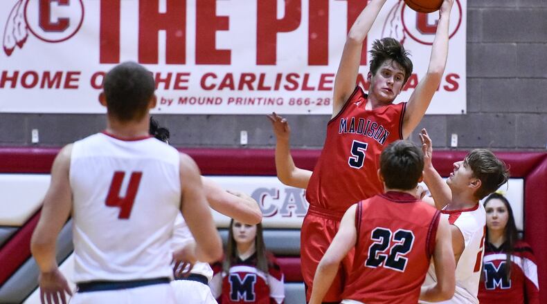 Madison’s Grant Whisman grabs a rebound in the vicinity of teammate Jake Phelps (22) and Carlisle’s Dane Flatter (4) on Friday night at Carlisle. The visiting Mohawks won 58-39. NICK GRAHAM/STAFF