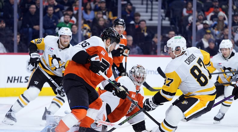 Pittsburgh Penguins' Sidney Crosby (87) scores a goal against Philadelphia Flyers' Dan Vladar (80) and Emil Andrae (36) during the first period of an NHL hockey game Monday, Dec. 1, 2025, in Philadelphia. (AP Photo/Matt Slocum)