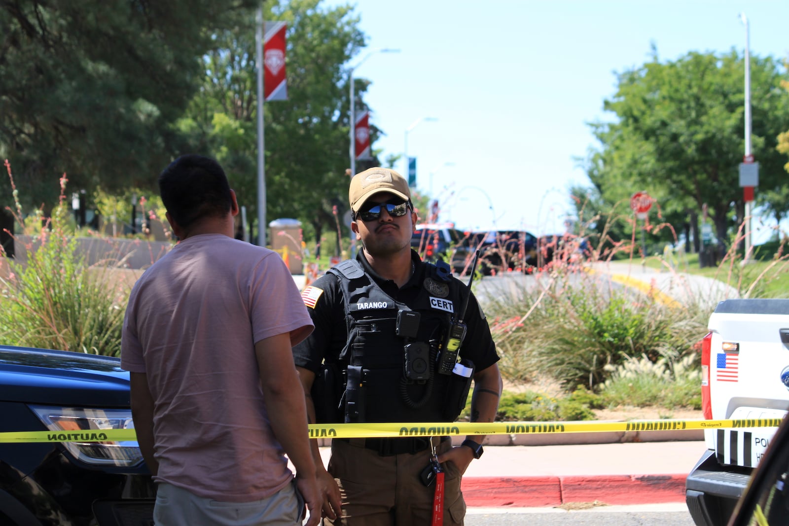 An officer talks to a delivery driver at a roadblock on the University of New Mexico campus where two people were shot, one of them fatally, in the early morning hours in Albuquerque, N.M., on Friday, July 25, 2025. (AP Photo/Susan Montoya Bryan)