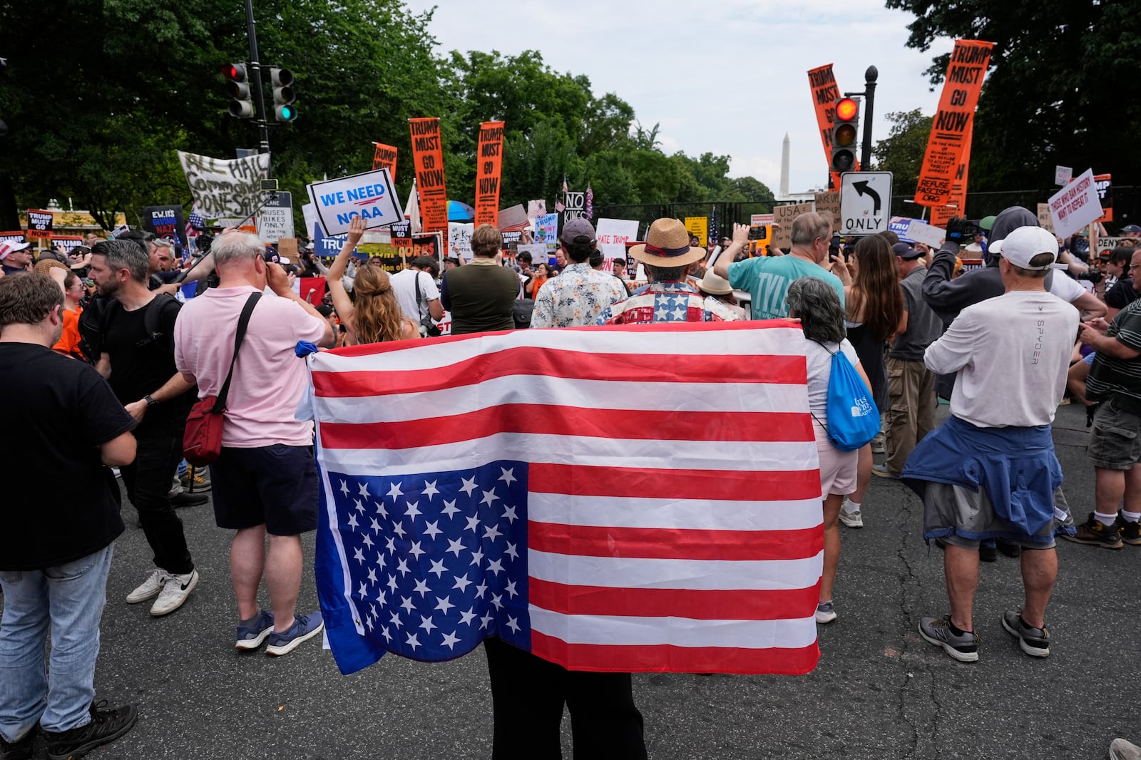 A demonstrator carries an American flag upside-down near the White House during a protest taking place on the day of a military parade commemorating the Army's 250th anniversary, coinciding with President Donald Trump's 79th birthday, Saturday, June 14, 2025, in Washington. (AP Photo/Alex Brandon)