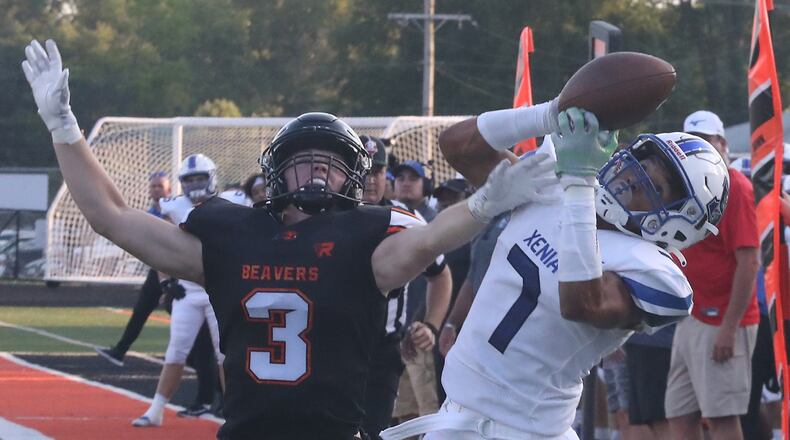 Xenia's Tremmell Wright Wright catches a first down pass under pressure from Beavercreek's Logan Spaeth during Friday night's season opener. BILL LACKEY/STAFF