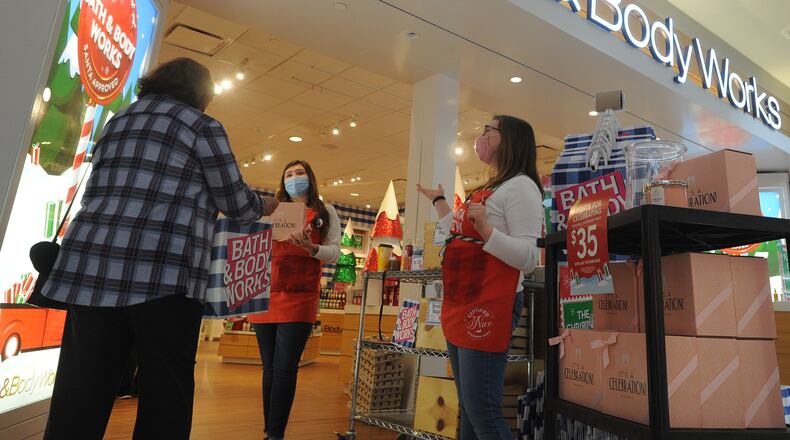 Cheyenne Water and Natalie Herrfurth, employees at Bath and Body Works at the Dayton Mall, greet customers as they walk into the store Dec. 18, 2020. The employees ask if they can assist shoppers by helping them find the items they are looking for. MARSHALL GORBY\STAFF