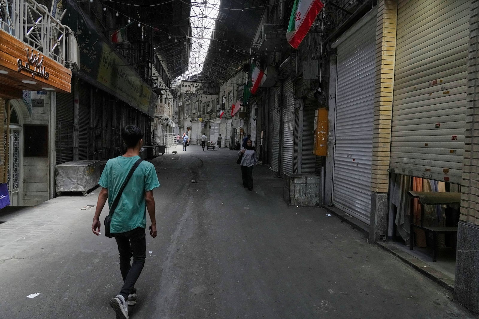 Few pedestrians walk along the historic Grand Bazaar as shops remain shuttered, in Tehran, Iran, Monday, June 16, 2025. (AP Photo/Vahid Salemi)