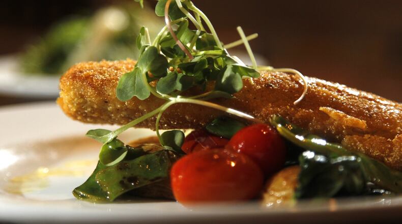 Locally grown microgreens on top of cornmeal crusted walleye with spring vegetable ragout at the Winds in Yellow Springs. LISA POWELL / STAFF