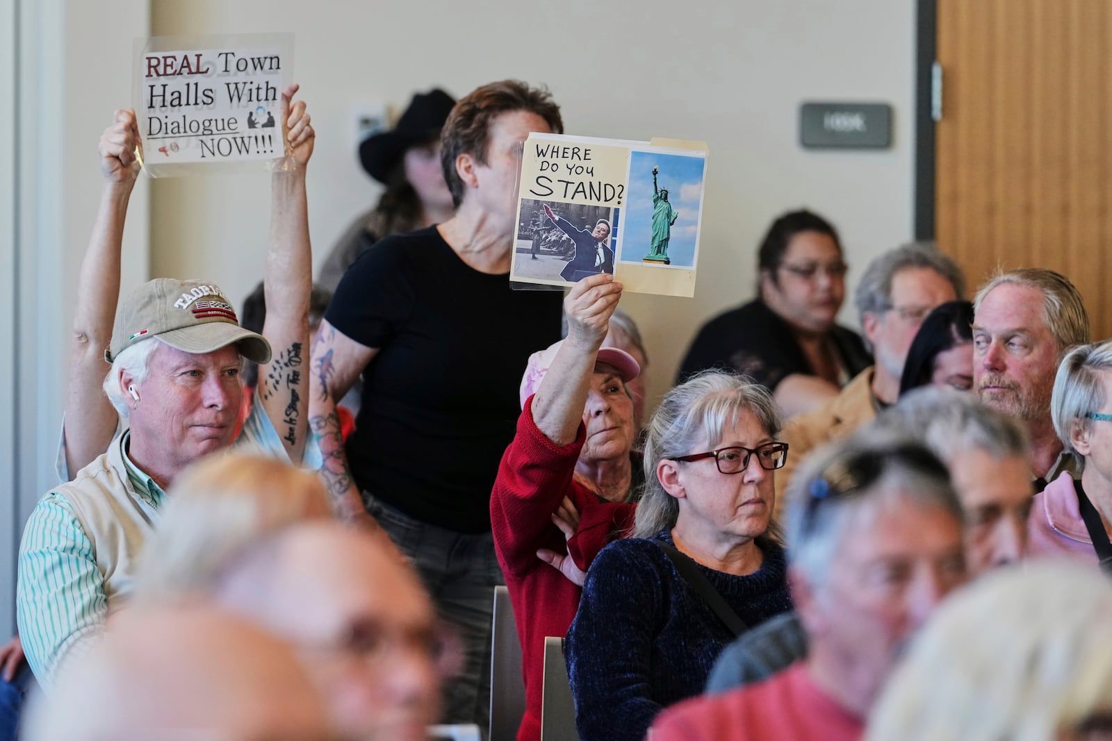 Linda Warren of Winlock, Wash., in red, holds up a sign during a town hall event with Rep. Marie Gluesenkamp Perez, D-Wash., at Centralia College, Tuesday, April 22, 2025, in Centralia, Wash. (AP Photo/Lindsey Wasson)