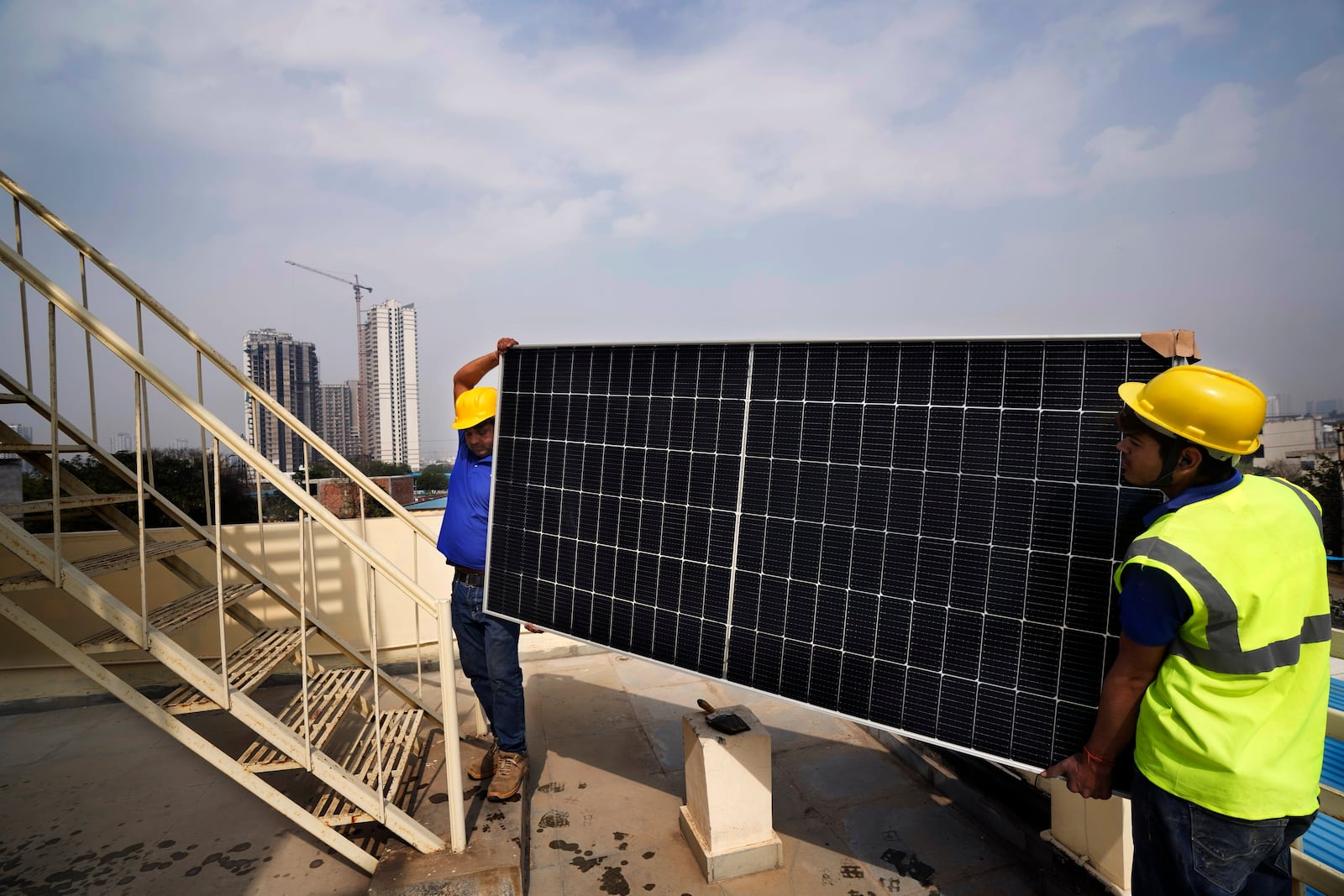 FILE - Workers of Solar Square carry a panel on the rooftop of a residence in Gurugram on the outskirts of New Delhi, India, Feb. 20, 2024. (AP Photo/Manish Swarup, File)