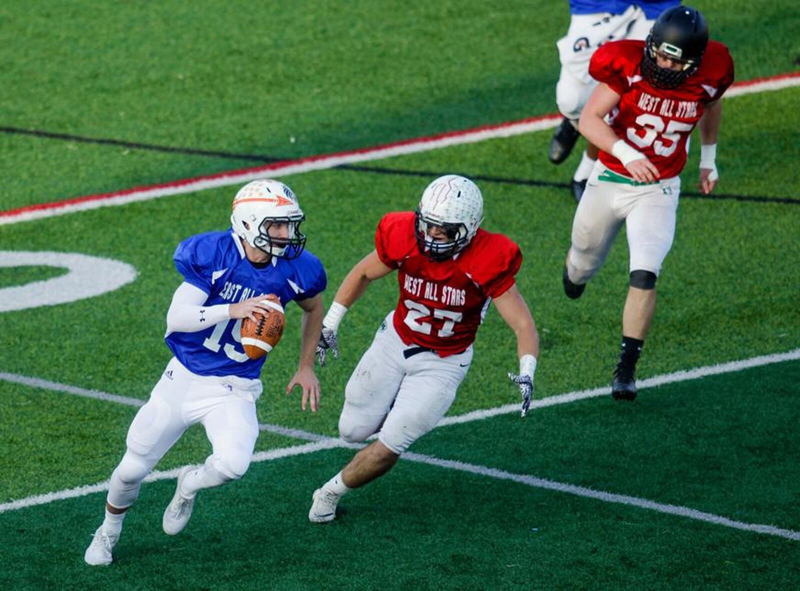 The West’s Kegen Rogers (27) of Badin chases East quarterback Blake King (15) of Milford during the 43rd Southwestern Ohio Football Coaches Association Ron Woyan East-West All-Star Game on Thursday night at Kings. NICK GRAHAM/STAFF