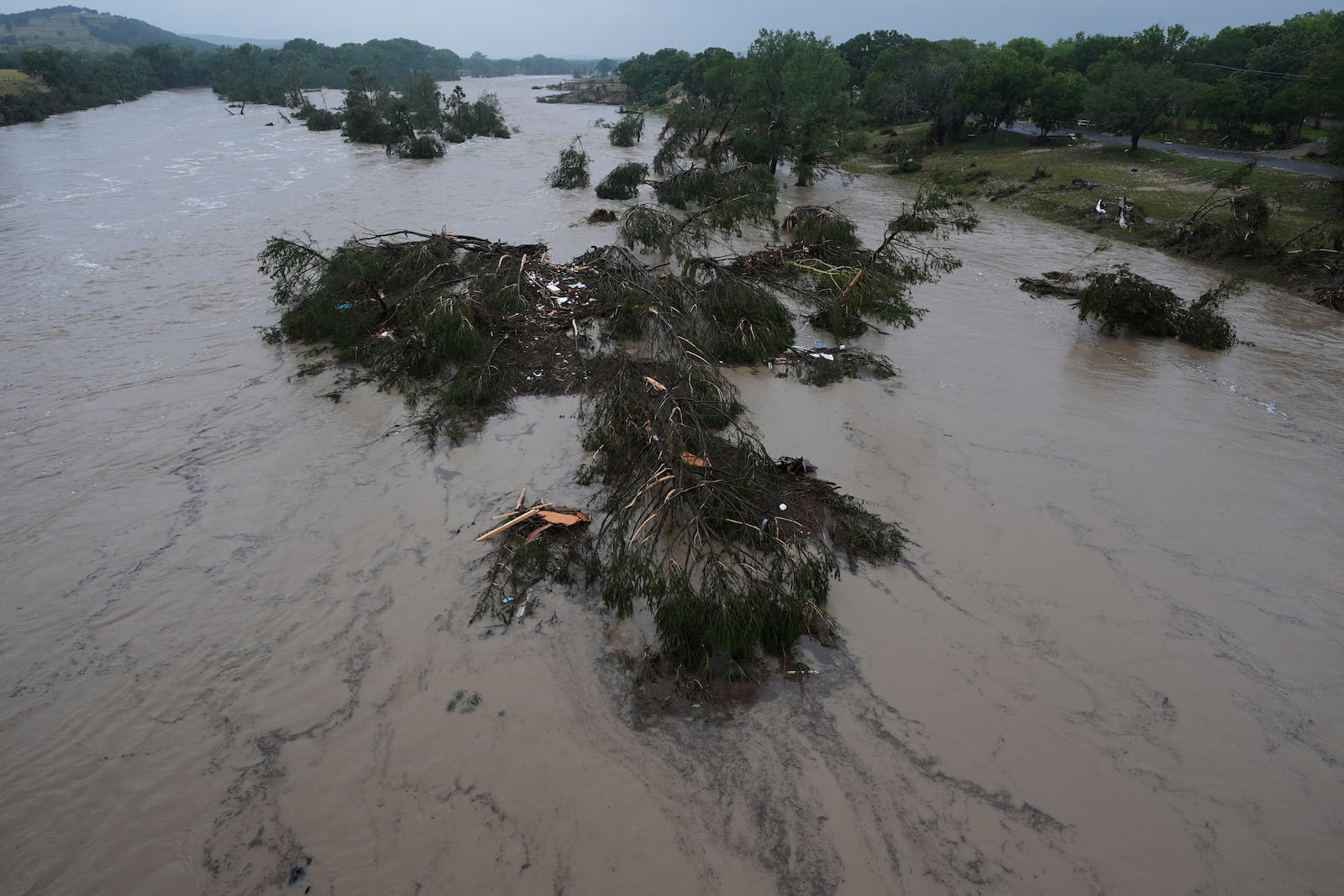 A raging Guadalupe River leaves fallen trees and debris in its wake, Friday, July 4, 2025, in Kerrville, Texas. (AP Photo/Eric Gay)