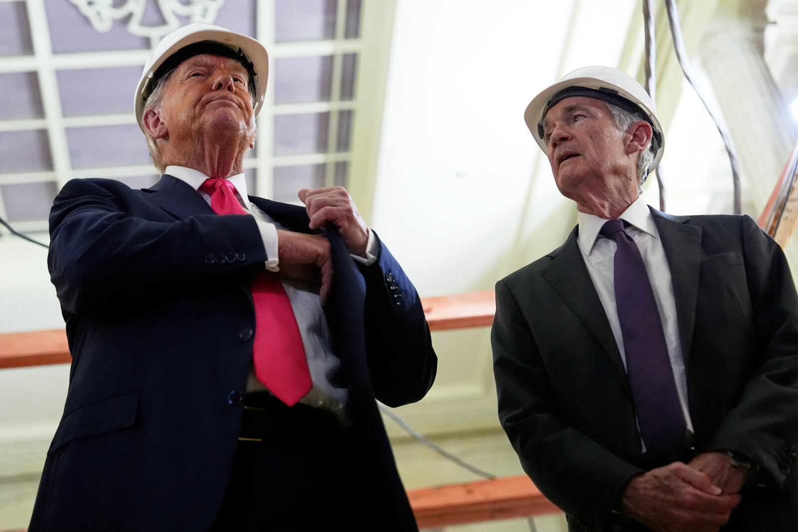 President Donald Trump, left, reaches for a document of cost figures as Federal Reserve Chairman Jerome Powell watches during a visit to the Federal Reserve, Thursday, July 24, 2025, in Washington. (AP Photo/Julia Demaree Nikhinson)