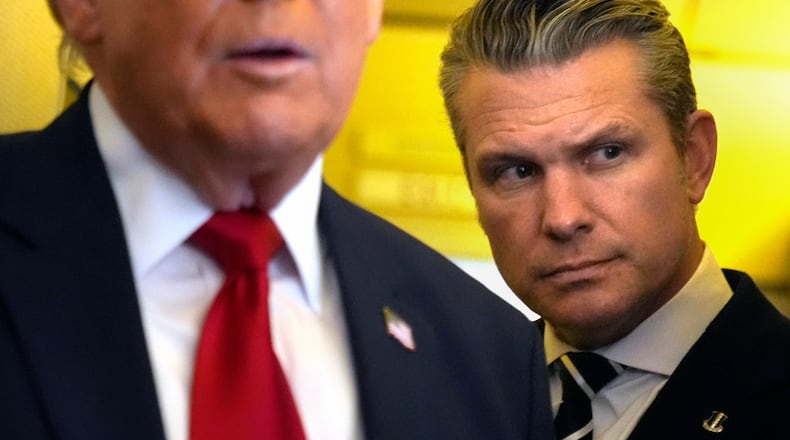 Defense Secretary Pete Hegseth listens as President Donald Trump speaks to reporters while traveling aboard Air Force One en route from Dover Air Force Base, Del., to Miami, Saturday, March 7, 2026. (AP Photo/Mark Schiefelbein)