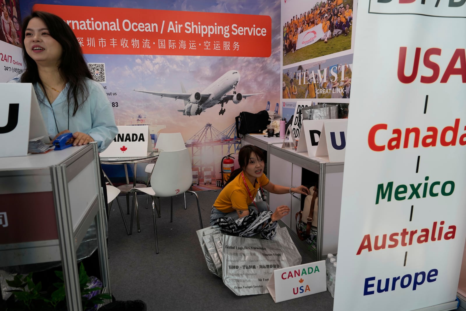 Angel Li, marketing senior sales executive with Great Link Logistics Co. Ltd, left, talks about logistics to the U.S. at the 137th Canton Fair in Guangzhou in southern China's Guangdong province on Wednesday, April 16, 2025. (AP Photo/Ng Han Guan)