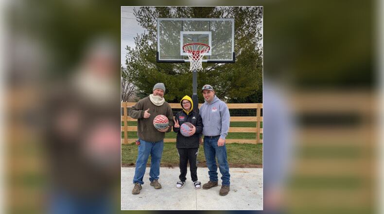 Kaden Buck, 17, of Trenton, stands with Hamilton firefighters Toby Howell and Ryan Pendergest, who helped organize an effort to build a basketball half-court space for the teen. PROVIDED