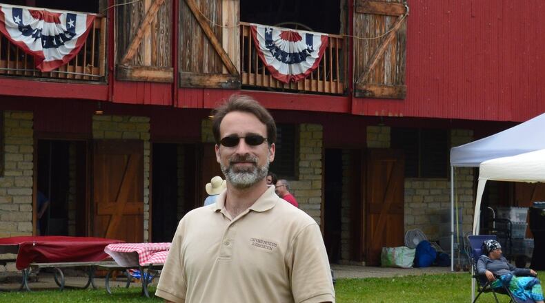 Michael Case has settled in to the role of Director of Programs and Properties for the Oxford Museum Association. He is shown with the Pioneer Barn in the background at last weekend’s Hueston Woods Arts & Crafts Fair. CONTRIBUTED/BOB RATTERMAN