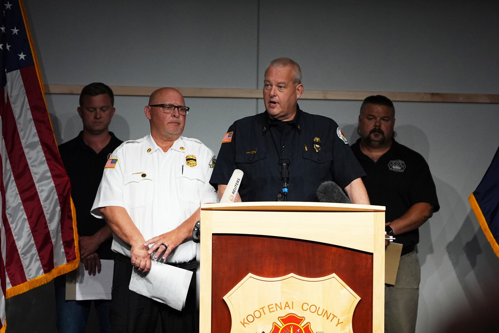 Kootenai County Fire & Rescue Chief Christopher Way, center, speaks as Coeur d'Alene Fire Chief Tom Greif, front left, looks on during a press conference announcing the names of the firefighters killed and wounded the day before by a shooter while responding to a wildfire at Canfield Mountain, Monday, June 30, 2025, in Post Falls, Idaho. (AP Photo/Lindsey Wasson)