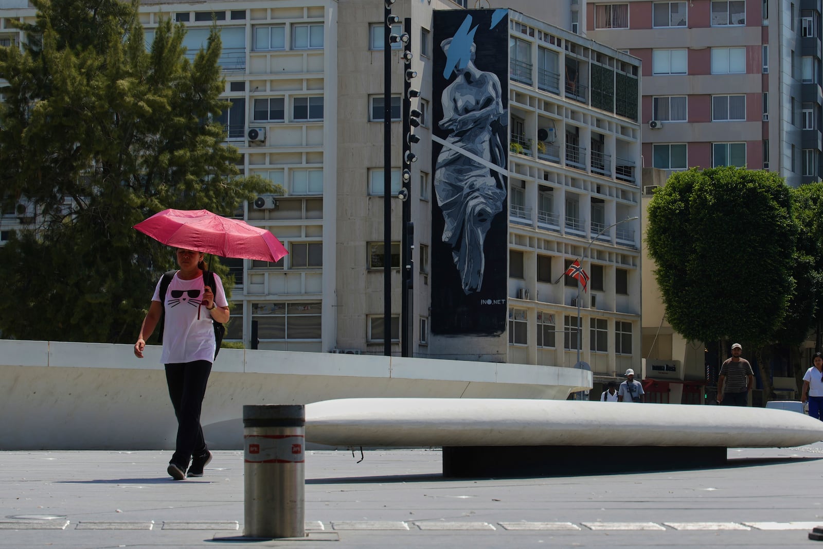 A woman uses an umbrella to protect herself from the sun during a hot day at Eleftherias square in central capital Nicosia, Cyprus, Friday, July 25, 2025. (AP Photo/Petros Karadjias)
