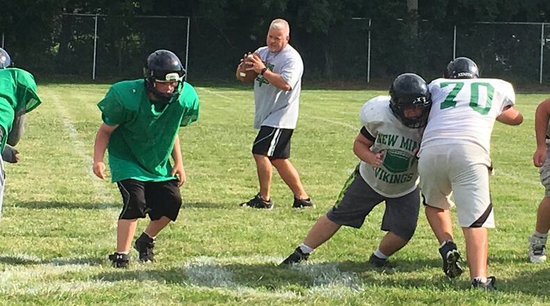 First-year New Miami High School football coach Jessie Hubbard runs through drills with his team during a recent practice at the school. RICK CASSANO/STAFF
