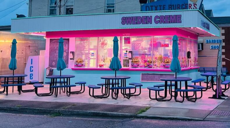 Sweden Creme in Lindenwald, a neighborhood of Hamilton, is painted pink and light blue, and the building is lit up with neon lights at night. Metal tables with built-in benches and umbrellas and picnic-table style seating are available outdoors. A new sign advertises the signature Dixie Burger. The windows are decorated with dancing Dixie Burgers and ice cream cones. CONTRIBUTED