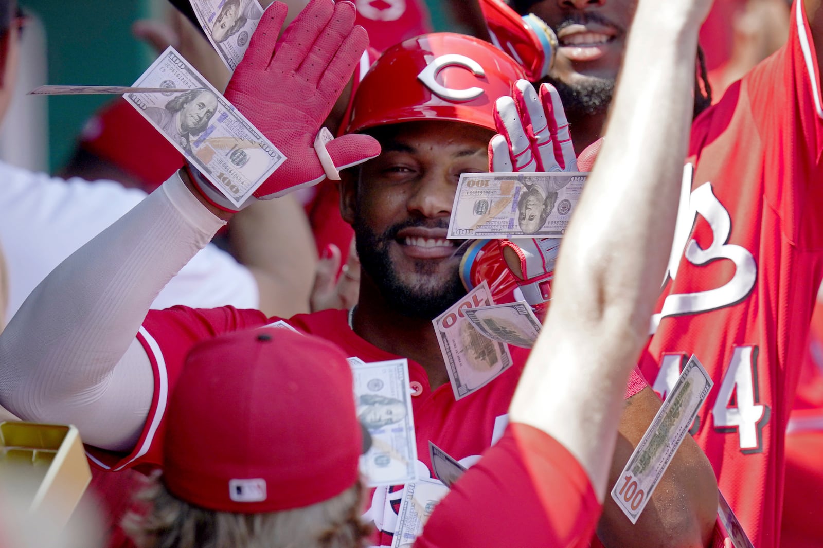 Teammates shower Cincinnati Reds' Miguel Andujar with play money in the dugout after his three-run home run during the third inning of a baseball game against the Pittsburgh Pirates, Sunday, Aug. 10, 2025, in Pittsburgh. (AP Photo/Matt Freed)