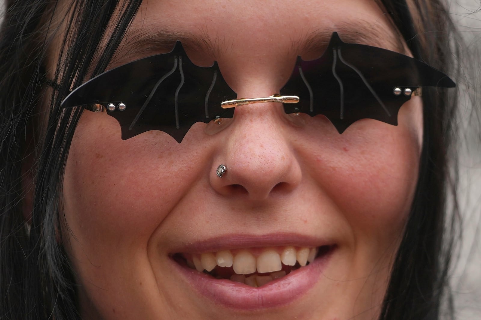 A music fan wears a sunglasses depicting bats to commemorate the death of Ozzy Osbourne at the Black Sabbath Bridge in Birmingham, Wednesday, July 23, 2025. (AP Photo/Kin Cheung)