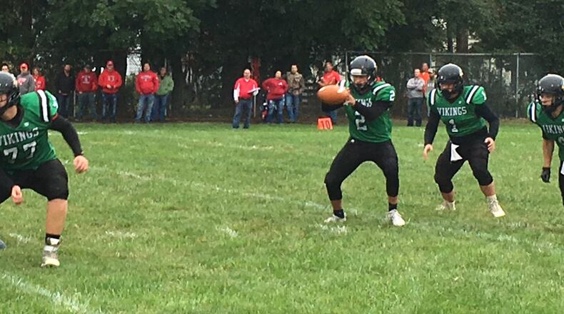 New Miami quarterback Trey Robinette gets the snap as teammate Bruce Montgomery (77) does some blocking up front during Saturday night’s game against Marion Elgin at Mara Field in New Miami. RICK CASSANO/STAFF