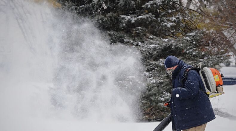 A Huber Heights resident blows fresh snow off the sidewalk and driveway along Fishburg Road Thursday, Feb. 18, 2021. MARSHALL GORBY\STAFF
