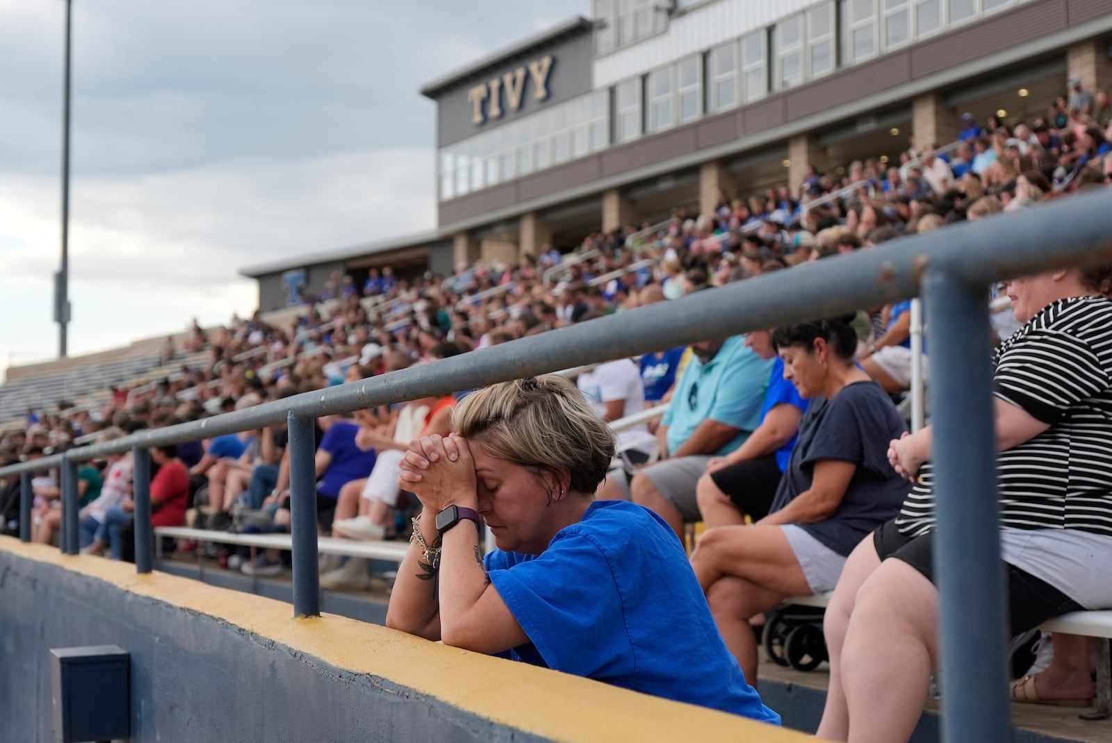 A woman prays during a vigil for flooding victims at Tivy Antler Stadium on Wednesday, July 9, 2025, in Kerrville, Texas. (AP Photo/Ashley Landis)
