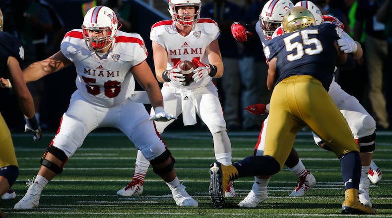 Miami quarterback Gus Ragland (14) takes a snap from center Mitch Palmer in the shotgun formation during the first half of an NCAA college football game Saturday, Sept. 30, 2017, in South Bend, Ind. (AP Photo/Charles Rex Arbogast)