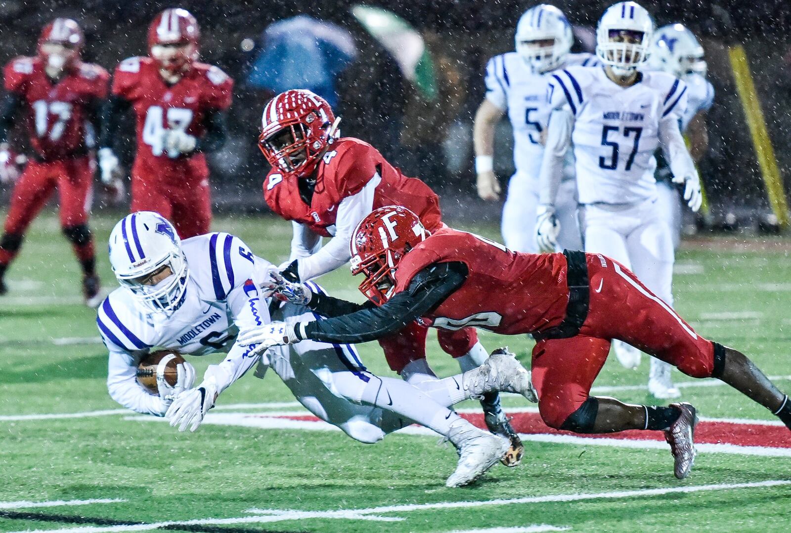 Middletown’s E.J. Hill makes a catch and is taken down by Fairfield’s Raqwon Williams (4) and Nashon Bell during Friday night’s game at Fairfield Stadium. NICK GRAHAM/STAFF