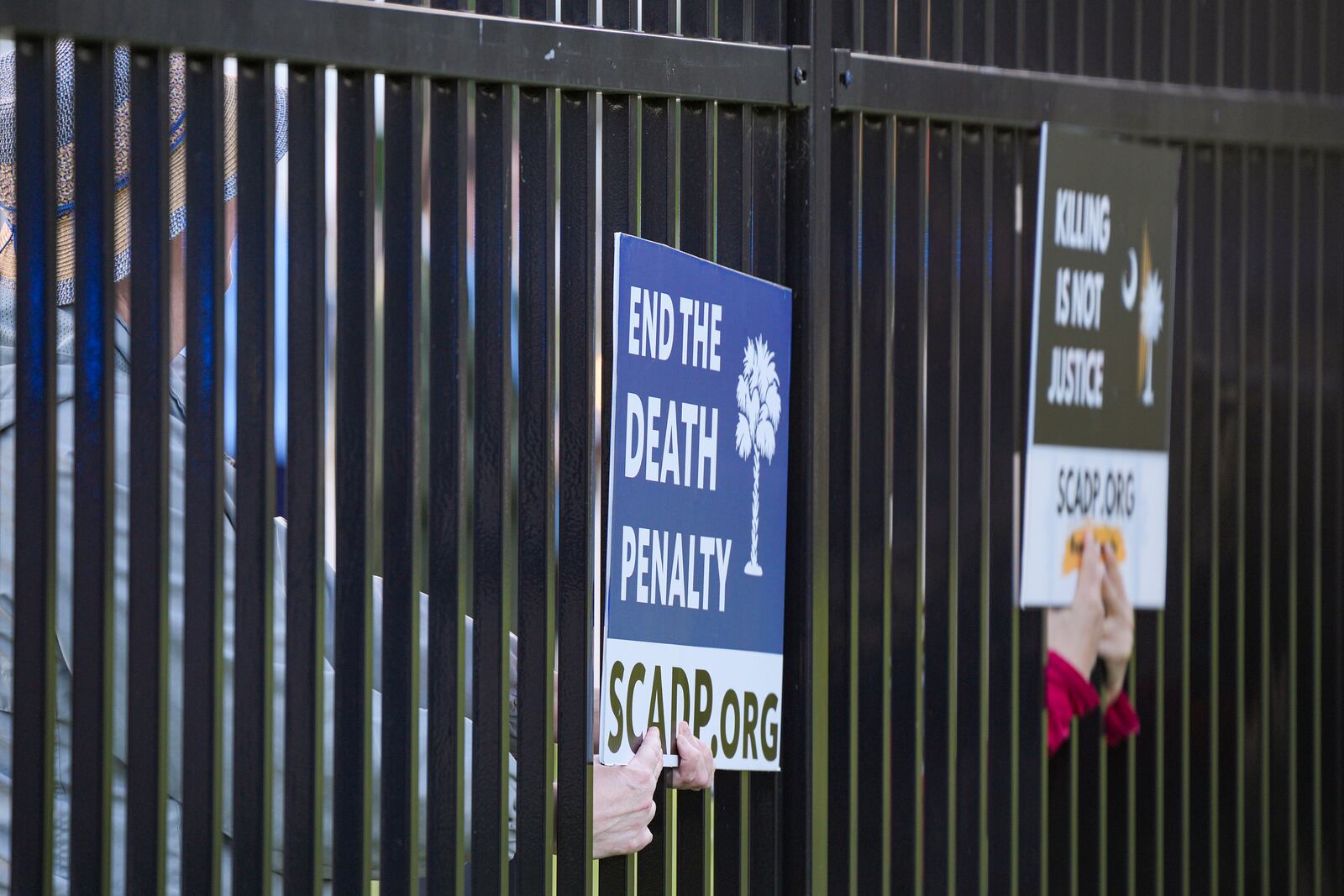 Protestors put their signs inside the Department of Corrections fence prior to the scheduled execution of South Carolina inmate Mikal Mahdi in Columbia, S.C., Friday, April 11, 2025. (AP Photo/David Yeazell)