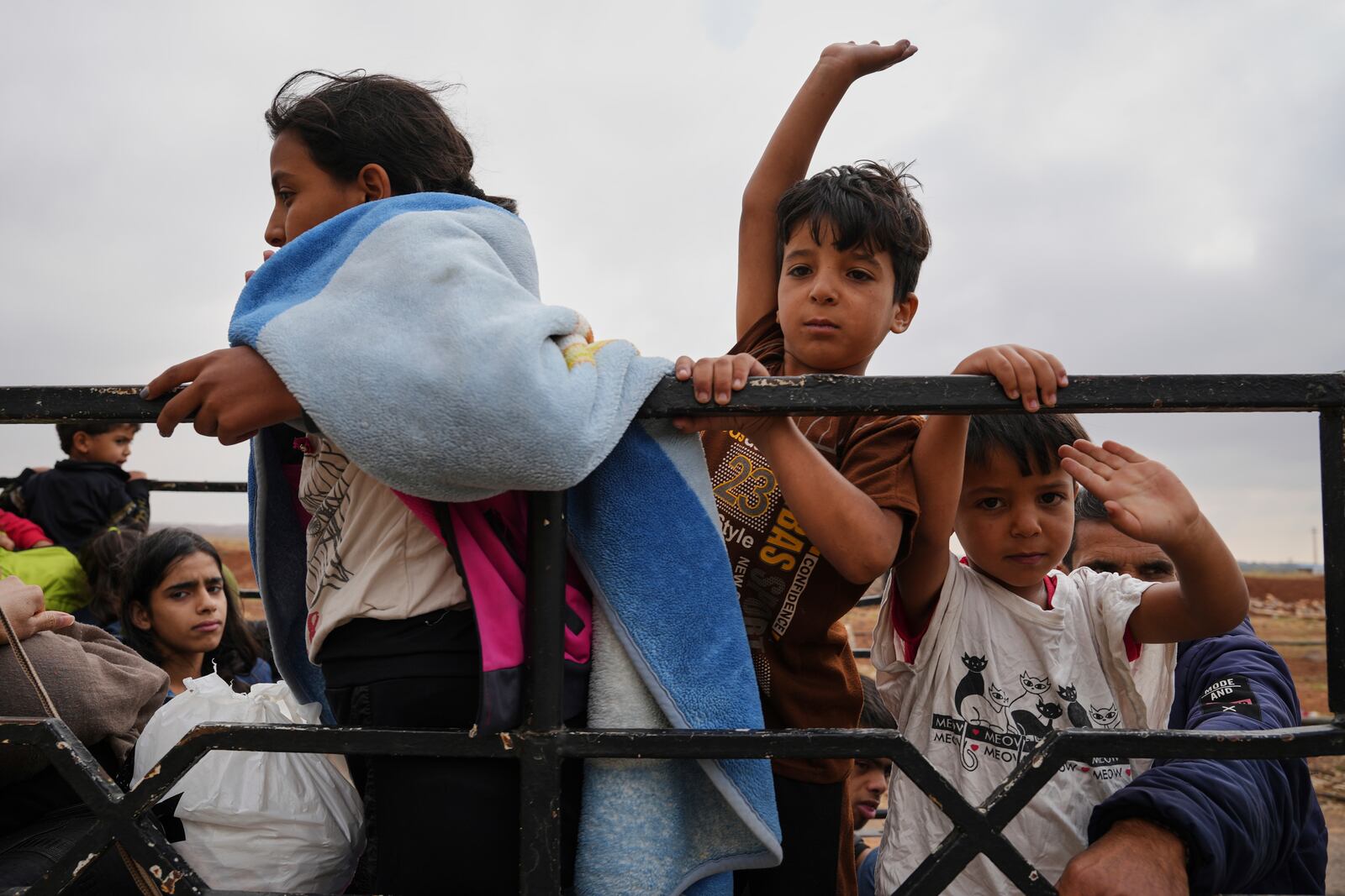 Syrian Bedouin families gesture as they ride in a convoy led by Red Crescent vehicles in Busra al-Harir, heading to Daraa after being evacuated from Sweida following more than a week of violent clashes, Monday, July 21, 2025. (AP Photo/Malek Khattab)