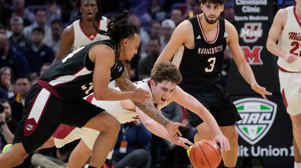 Miami (Ohio) guard Peter Suder, center, dives for the ball next to Massachusetts guard Marcus Banks, left, in the second half of a basketball game in the quarterfinals of the Mid-American Conference tournament, Thursday, March 12, 2026, in Cleveland. (AP Photo/Sue Ogrocki)