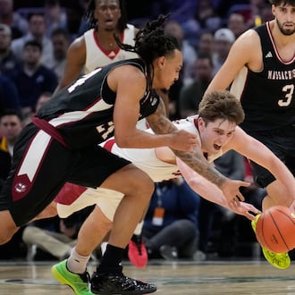Miami (Ohio) guard Peter Suder, center, dives for the ball next to Massachusetts guard Marcus Banks, left, in the second half of a basketball game in the quarterfinals of the Mid-American Conference tournament, Thursday, March 12, 2026, in Cleveland. (AP Photo/Sue Ogrocki)