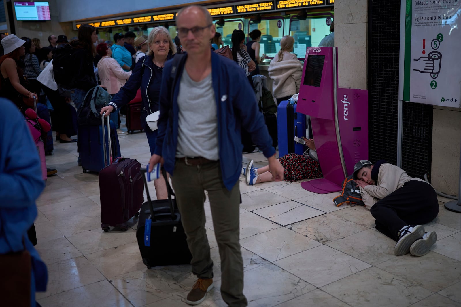 Passengers crowd the train accesses as other sleep at the ground at Sants train station in Barcelona, Spain, Tuesday, April 29, 2025. (AP Photo/Emilio Morenatti)