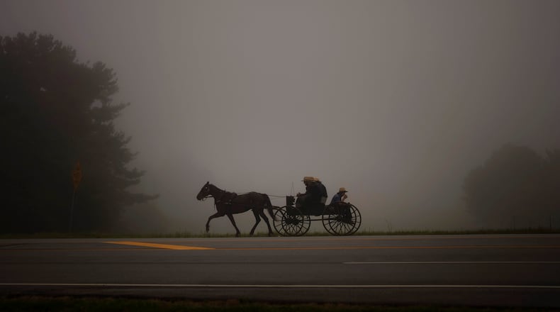 An Amish horse and buggy cross a road near Fremontin in Steuben County, Ind., Tuesday, Aug. 17, 2021. (AP Photo/Emilio Morenatti)