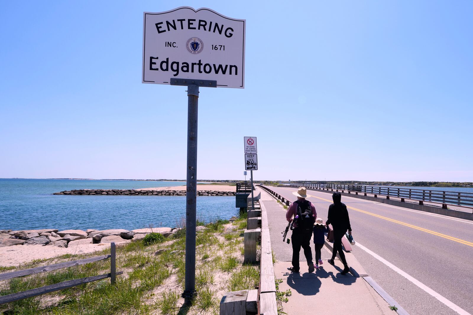 A family walks to the span of the American Legion Memorial Bridge, also known as the "Jaws Bridge", while spending the day fishing, Monday, May 12, 2025, in Edgartown, Mass., on Martha's Vineyard Island. (AP Photo/Charles Krupa)