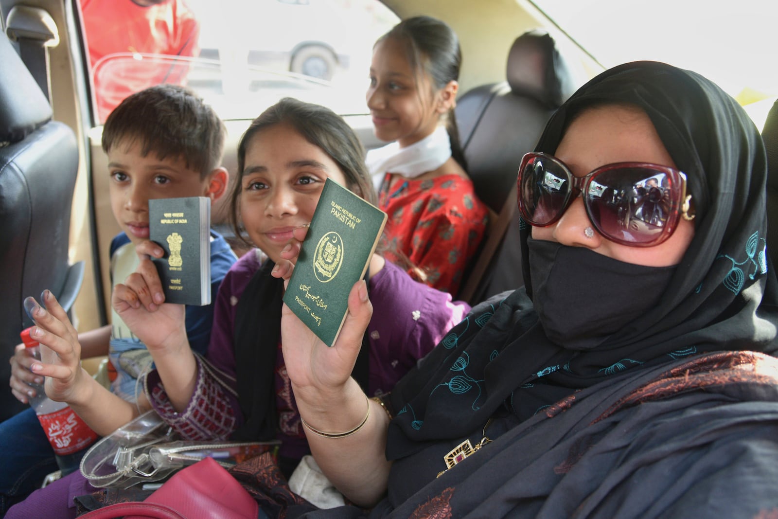 Pakistani national Khalida Hanif, right, and her Indian children display their passports on their return from Pakistan at the Attari-Wagah border between India and Pakistan, near Amritsar, India, Tuesday, April 29, 2025. (AP Photo/Prabhjot Gill)
