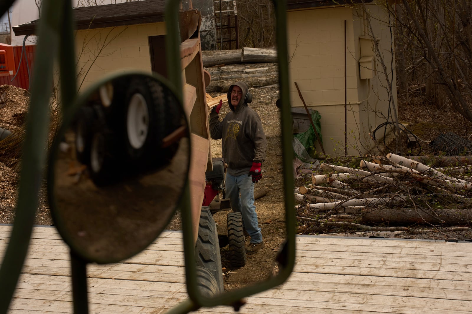 Morris Demoski tosses a split log into the back of a dump truck Thursday, May 22, 2025, in Galena, Alaska. (AP Photo/John Locher)