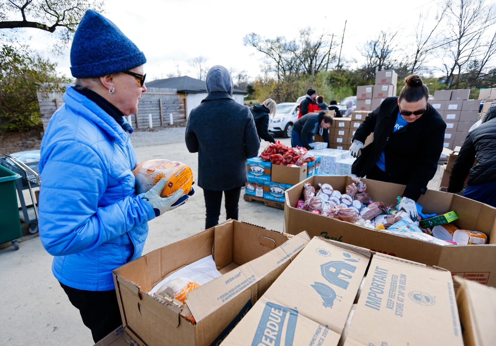 Volunteers and employees at Shared Harvest food Bank distribute food for around 250 families Friday, Nov. 18, 2022 in Fairfield. Volunteer Sandy Murawski, left, was handing out frozen chickens.  NICK GRAHAM/STAFF