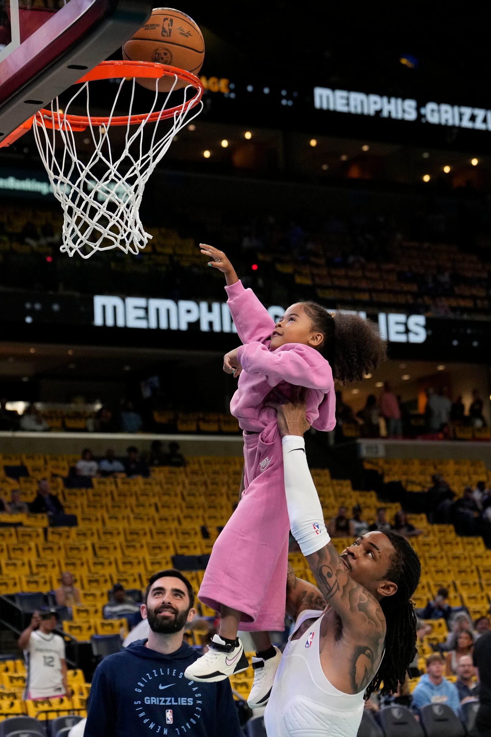 Memphis Grizzlies guard Ja Morant helps his daughter Kaari Morant shoot a basket before an NBA play-in tournament basketball game against the Dallas Mavericks, Friday, April 18, 2025, in Memphis, Tenn. (AP Photo/George Walker IV)