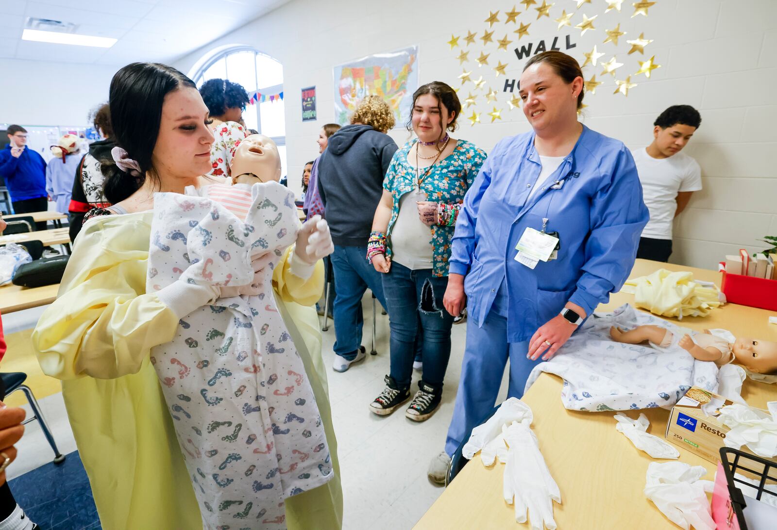 Madison Taylor learns to swaddle a baby doll during an adopt a class session with help from Jennifer Simmons, assistant nurse manager in the Obstetrics and Gynecology department at Kettering Health Hamilton, at Wilson Middle School Friday, April 11, 2025 in Hamilton. NICK GRAHAM/STAFF