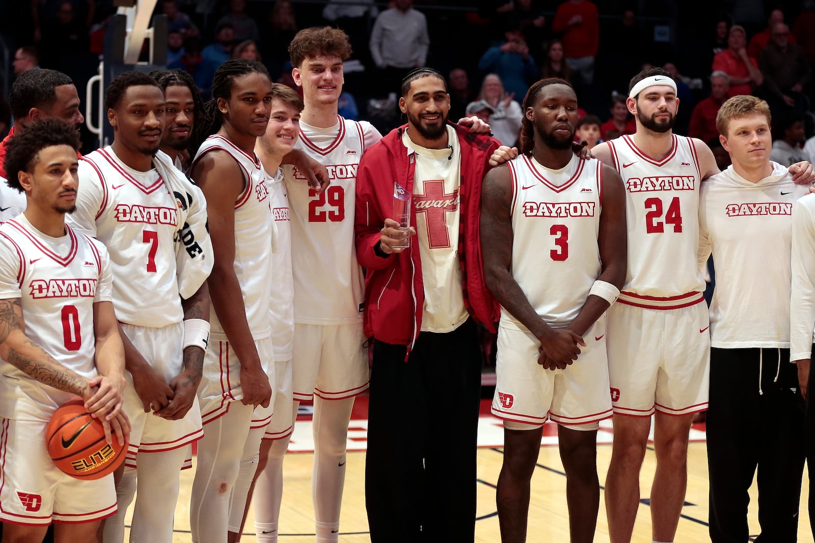 Members of Dayton's current roster gathered around former Flyer Obi Toppin for a photo opportunity as they came out of the locker room at halftime during a game against North Florida on Saturday, Dec. 13, 2025, at UD Arena. STEVEN WRIGHT / STAFF