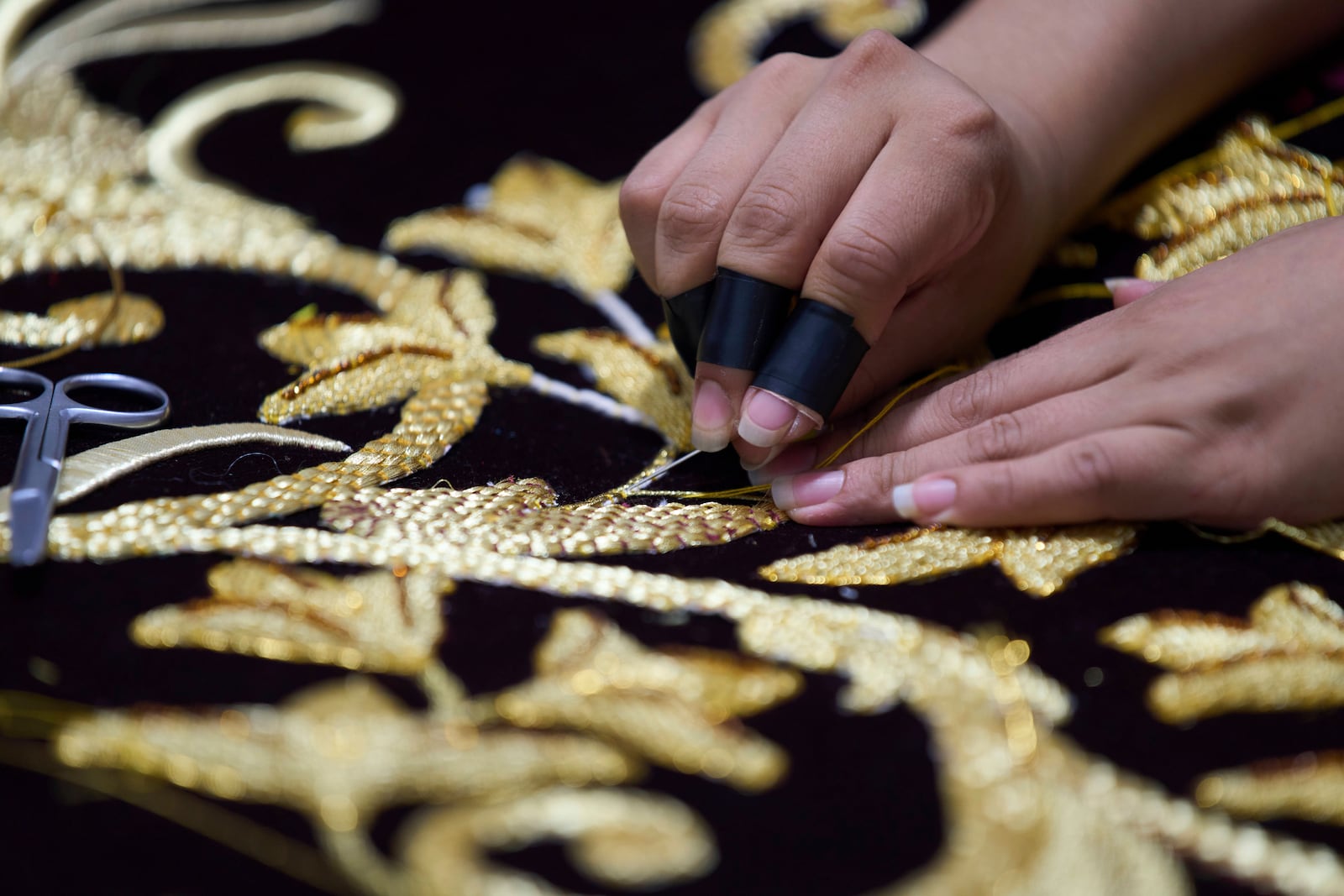 A weaver applies gold-colored pieces to the tunic for a statue of the Virgin Mary at the Maria Auxiliadora embroidery workshop in San Miguel Escobar, Guatemala, Wednesday, April 2, 2025. (AP Photo/Moises Castillo)
