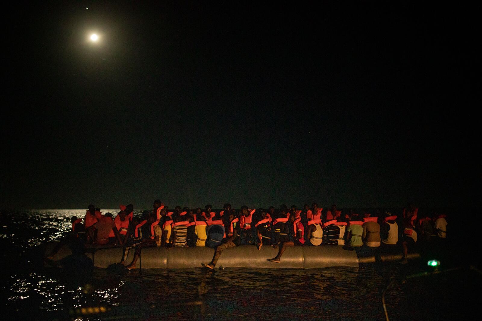 Men from different African nationalities wait to be assisted by crew members of the Louise Michel and Astral rescue vessels, after being located sailing adrift on an overcrowded rubber boat, 70 miles southwest Malta, in the Central Mediterranean sea, Saturday, Aug. 29, 2020. A rescue ship painted and sponsored by British artist Banksy saved another 130 migrants stranded on a rubber boat in the Southern Mediterranean Sea. (AP Photo/Santi Palacios)