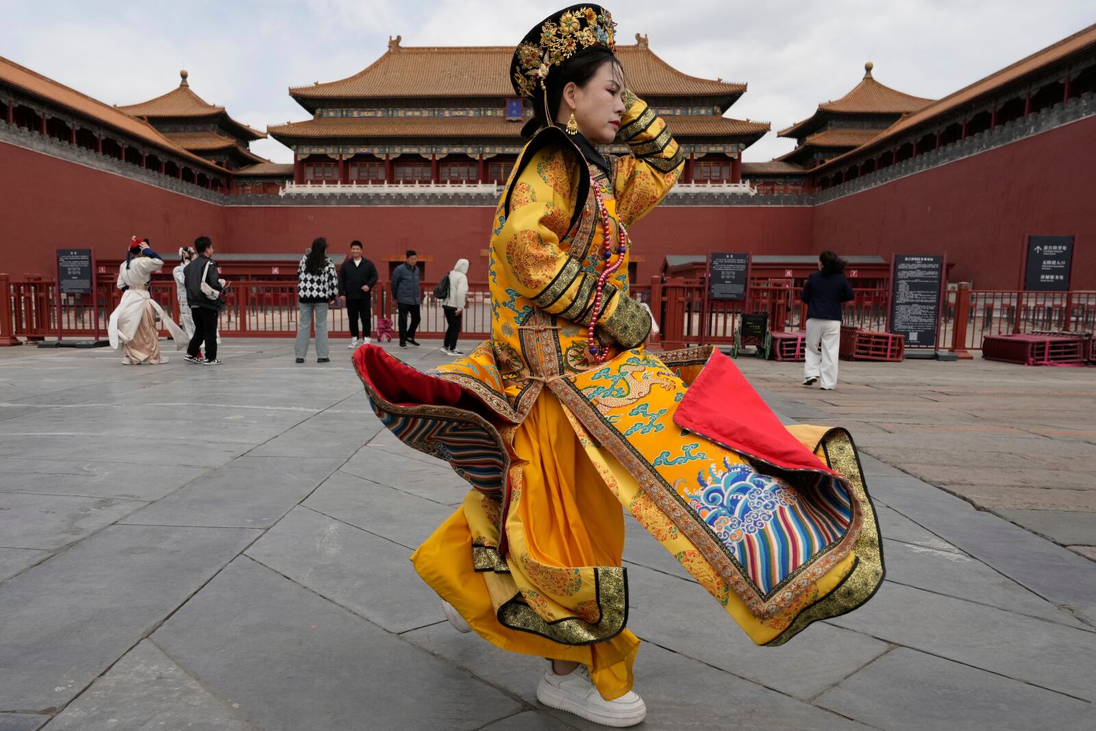 A woman dressed as the dowager reacts to strong winds outside the Forbidden City which was closed due to gale wind alerts in Beijing, China, Saturday, April 12, 2025. (AP Photo/Ng Han Guan)