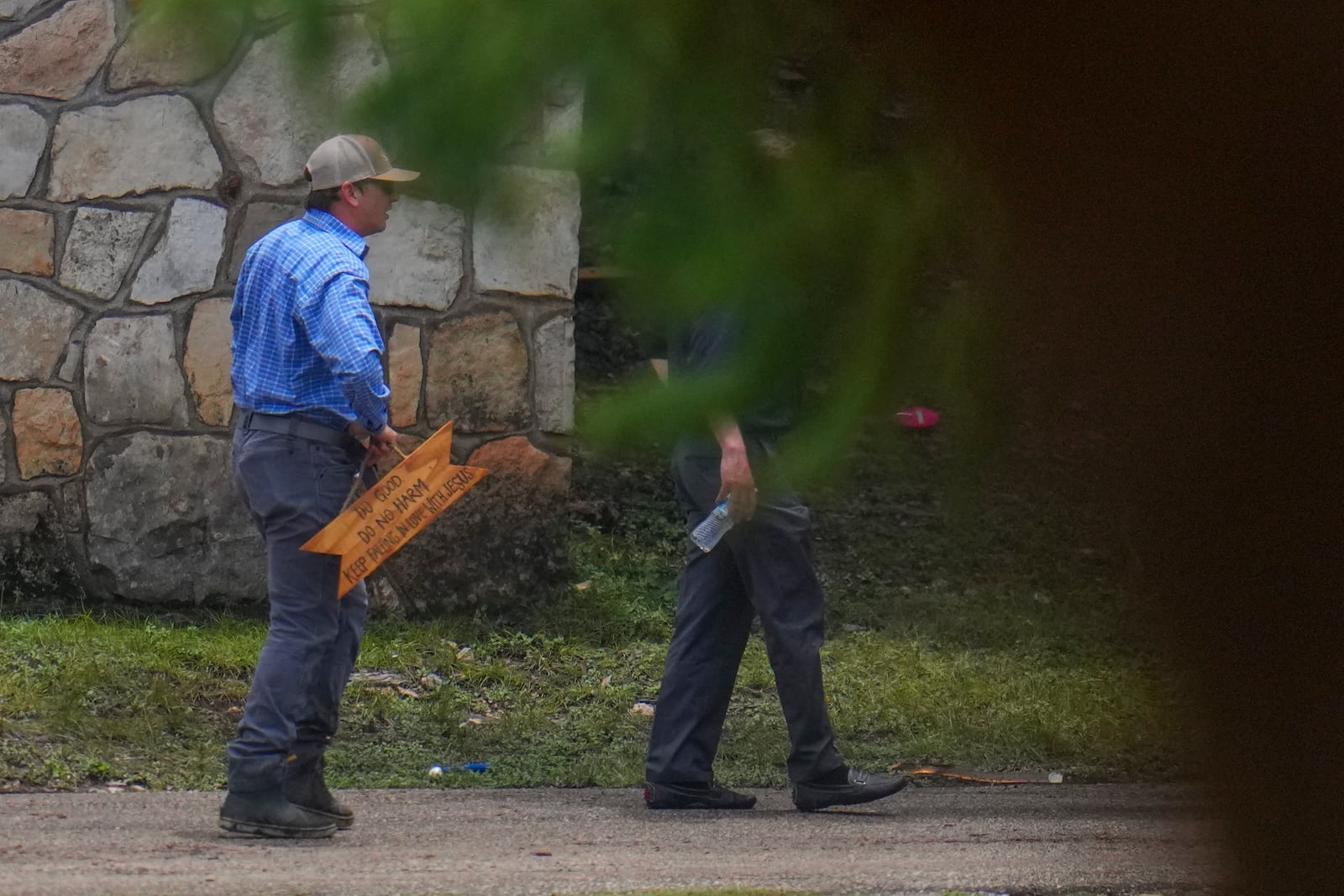 A person carries a sign reading "Do Good. Do No Harm. Keep Falling In Love with Jesus" after it was salvaged from debris washed up near Camp Mystic along the Guadalupe River after a flash flood on Friday swept through the area, Sunday, July 6, 2025, in Hunt, Texas. (AP Photo/Julio Cortez)