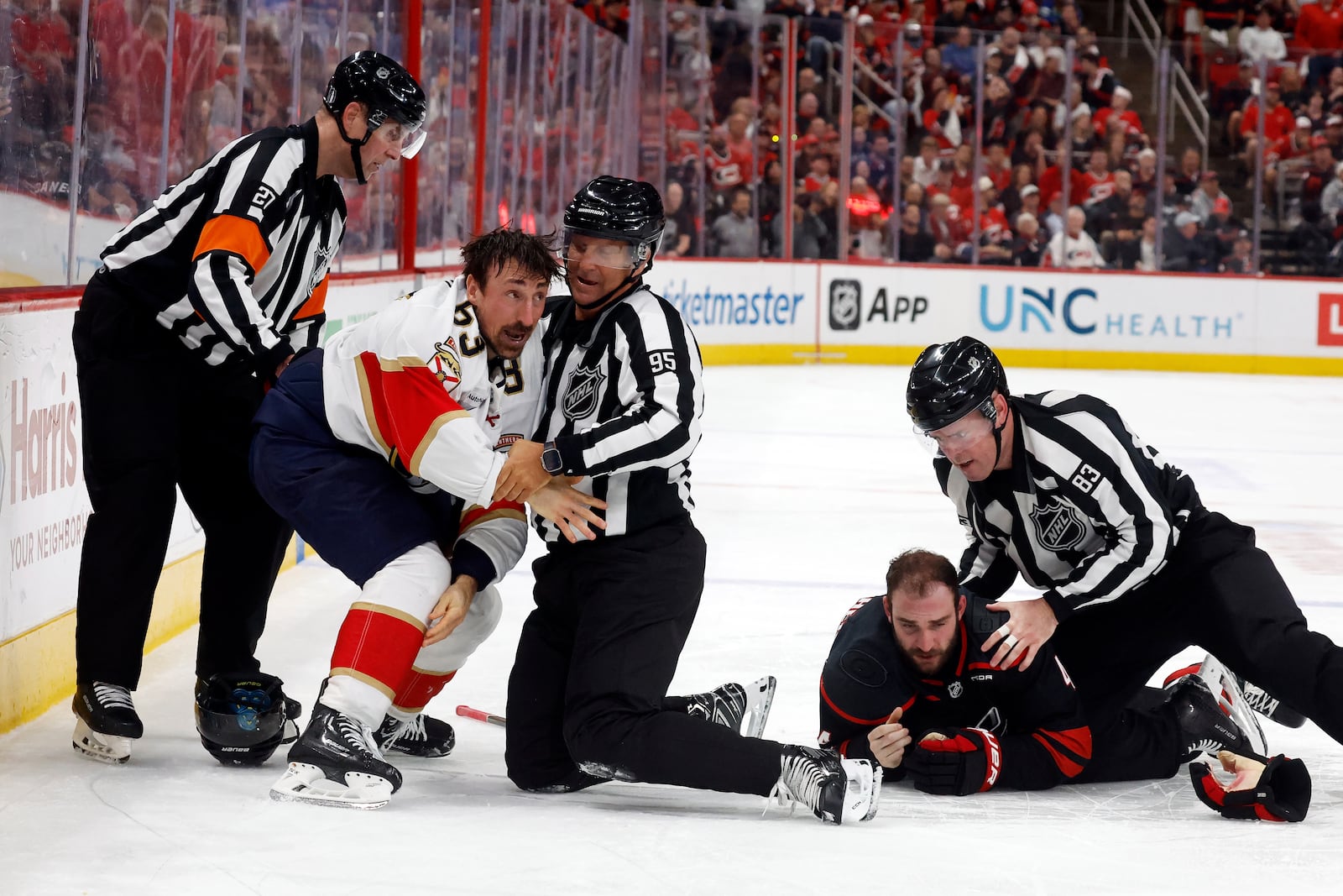 Florida Panthers' Brad Marchand, left, is separated by officials from Carolina Hurricanes' Shayne Gostisbehere (4) during the third period of Game 1 of the NHL hockey Stanley Cup Eastern Conference finals in Raleigh, N.C., Tuesday, May 20, 2025. (AP Photo/Karl DeBlaker)