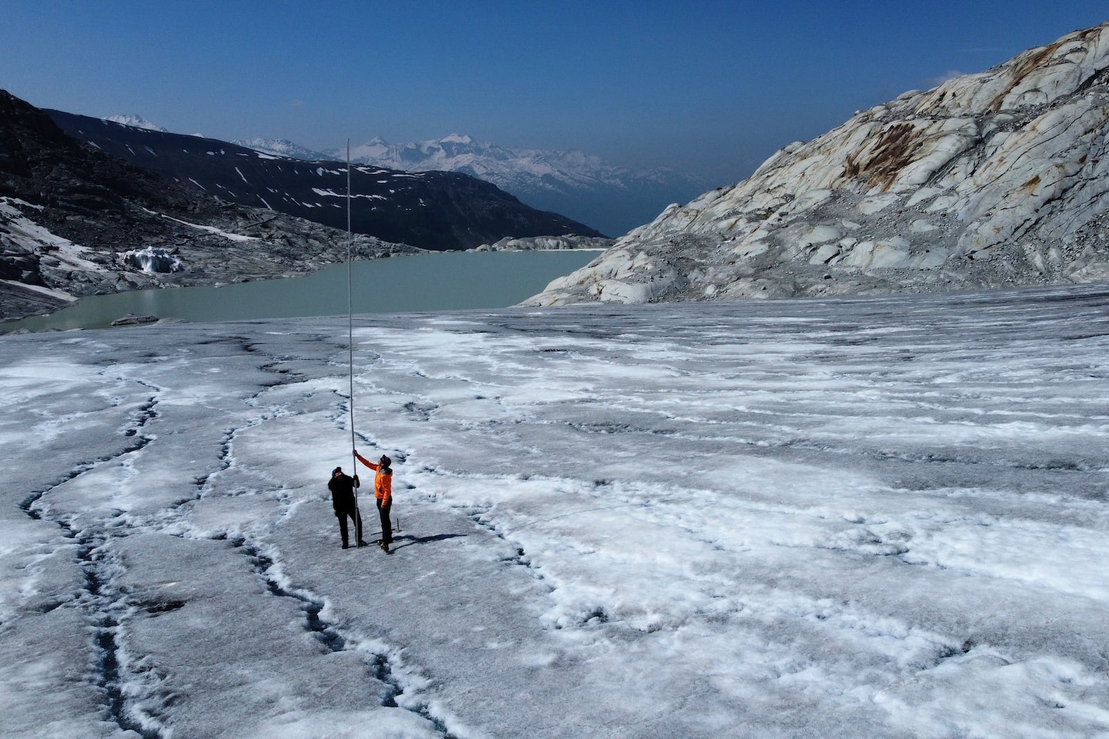 Matthias Huss, of the Federal Institute of Technology in Zurich and glacier monitoring group GLAMOS, and Monica Ursina Jaeger make measurements at the Rhone glacier near Goms, Switzerland, June 10, 2025. (AP Photo/Matthias Schrader)