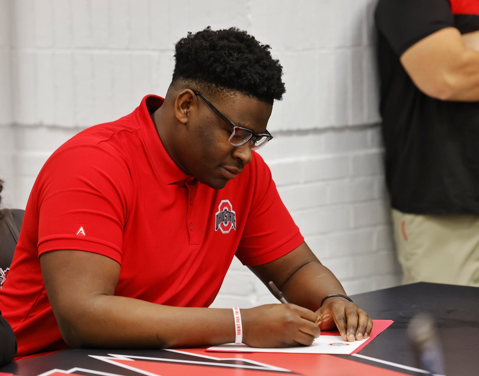 Lakota West's Tegra Tshabola sits during a national letter of intent college football signing ceremony Wednesday, Dec. 15, 2021 at Lakota West High School. Tshabola is signing with The Ohio State University. NICK GRAHAM / STAFF