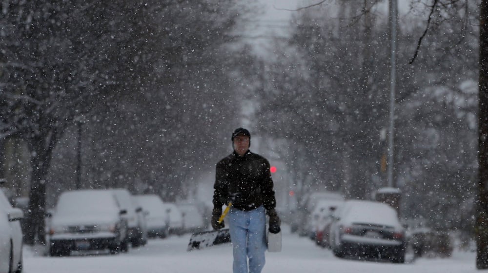 Jim Minutilli of Dayton carries a shovel and salt to take care of sidewalks covered with falling snow. STAFF PHOTO BY LISA POWELL
